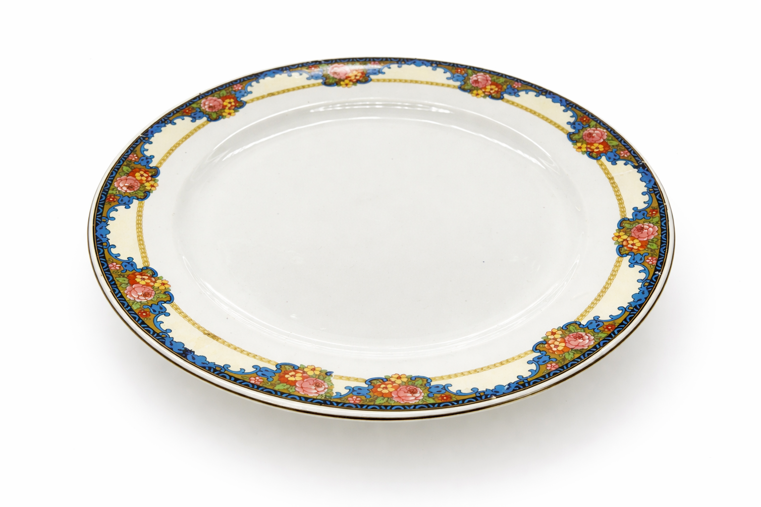 Assiette grande taille ancienne en faïence de Sarreguemines, décor floral stylisé, vue en perspective mettant en valeur la forme et la bordure décorée