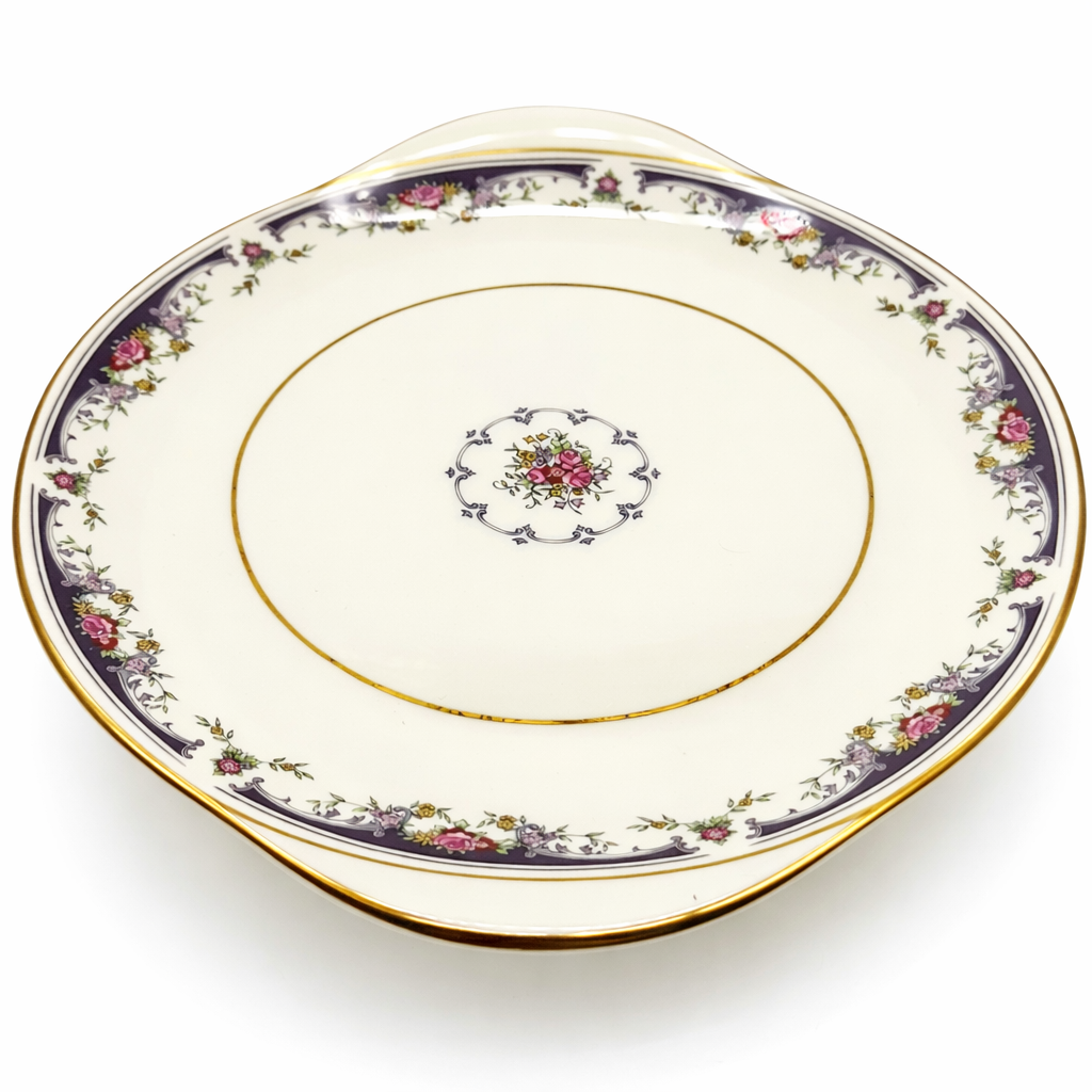 Vue de profil d’une assiette plate en porcelaine à décor floral et bord doré