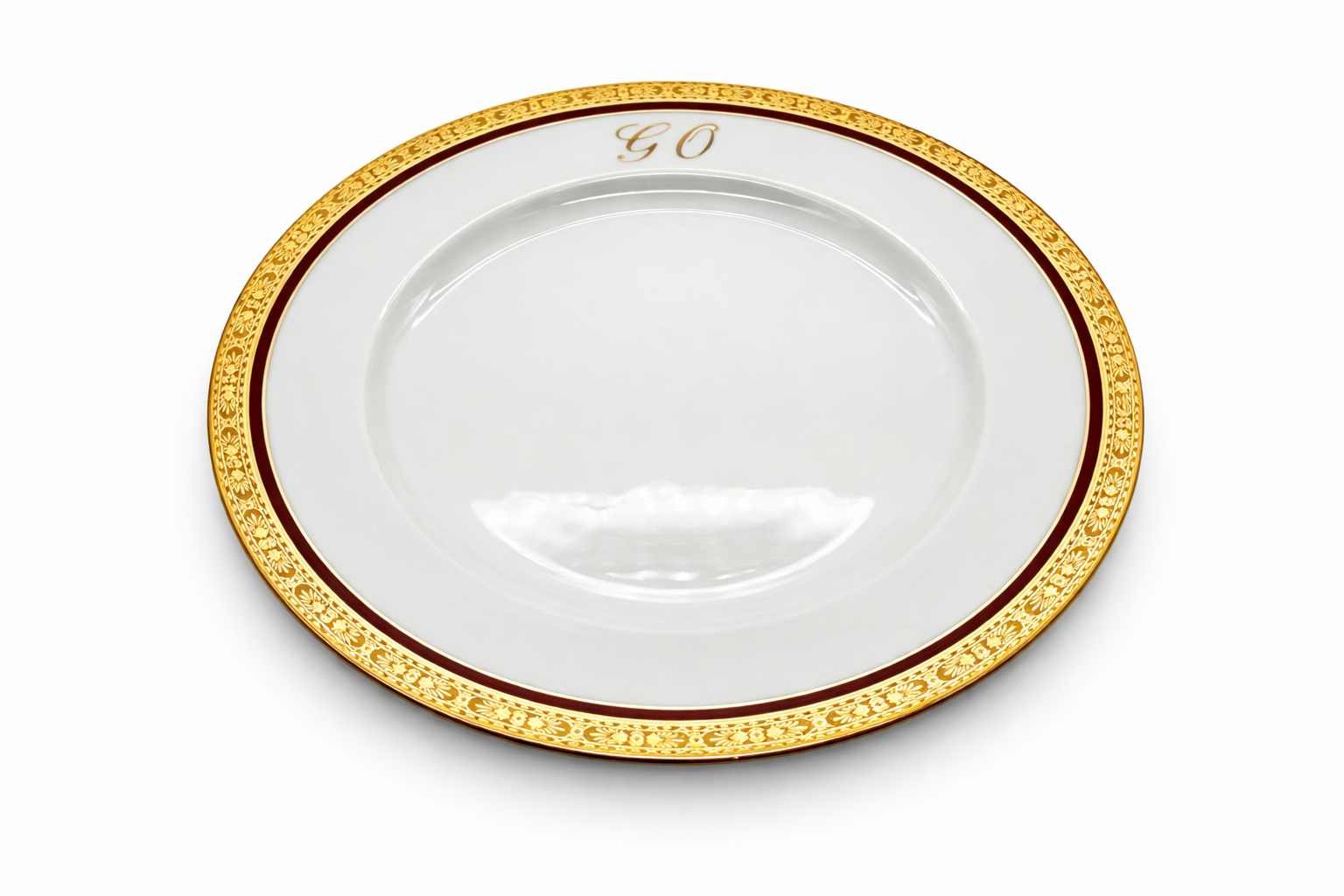 Assiette plate en porcelaine de Limoges vue en perspective, bordure dorée richement décorée et monogramme « GO »