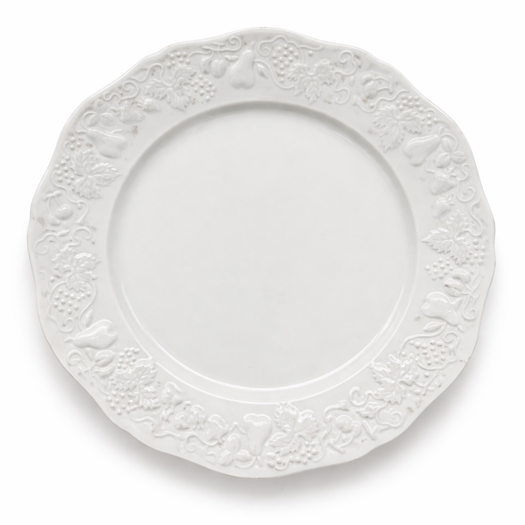 Assiette ancienne en porcelaine blanche, large décor en relief à motifs de fruits et feuillages, forme chantournée, vue de dessus