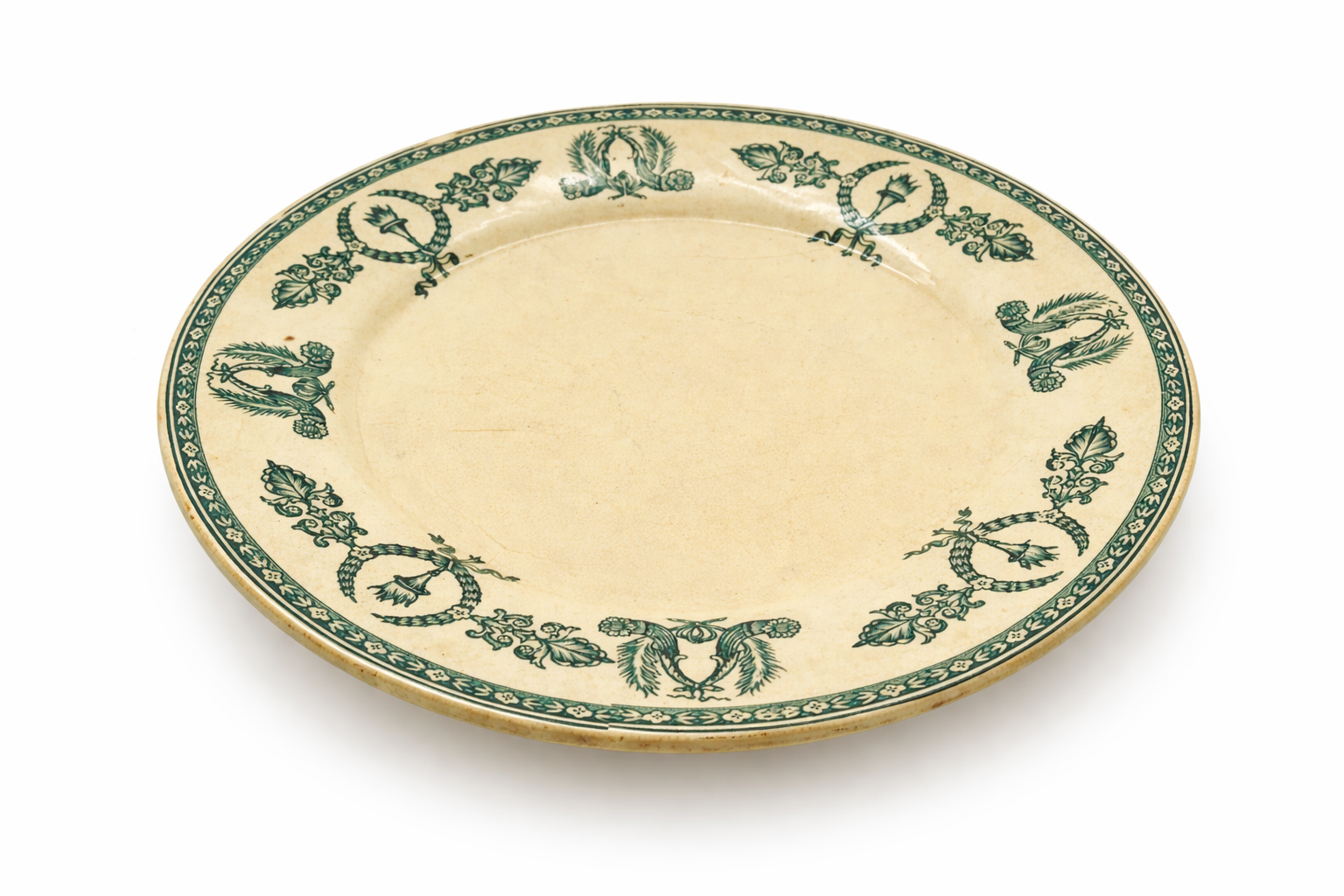 Assiette en faïence fine ancienne, décor vert imprimé avec couronnes et feuillages, patine du temps visible