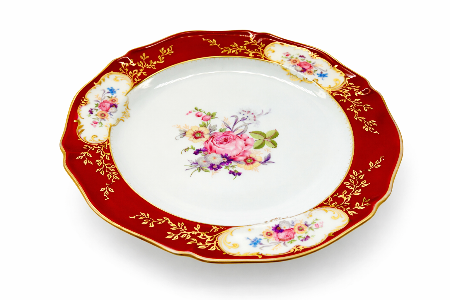 Assiette ancienne en porcelaine de Limoges vue en perspective, décor floral central et bordure rouge et or finement travaillée
