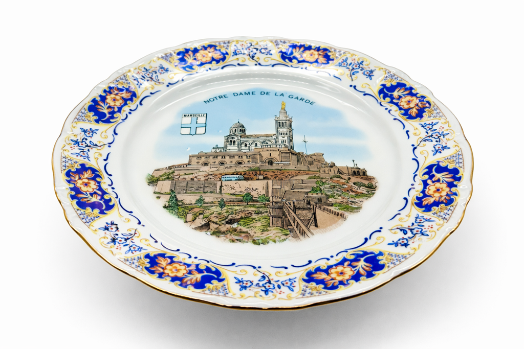 Assiette ancienne en porcelaine illustrée de Notre-Dame de la Garde, vue emblématique de Marseille avec frise florale et bord festonné