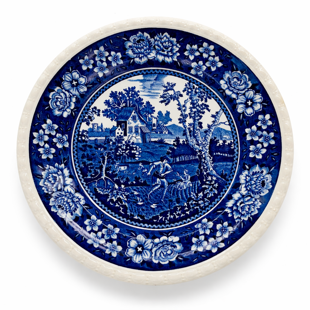 Assiette ancienne en céramique à décor bleu, scène champêtre et bordure florale, vue de dessus